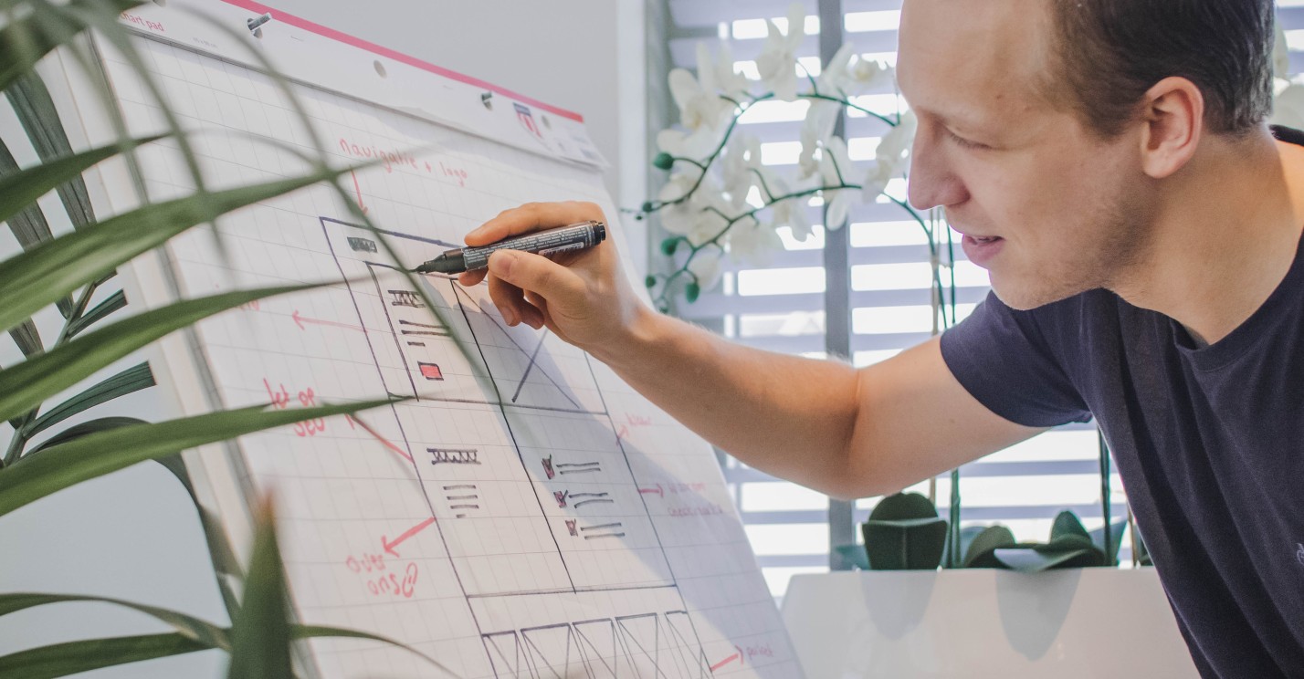 Websteen medewerker die de werking van online marketing uittekent op een bord.